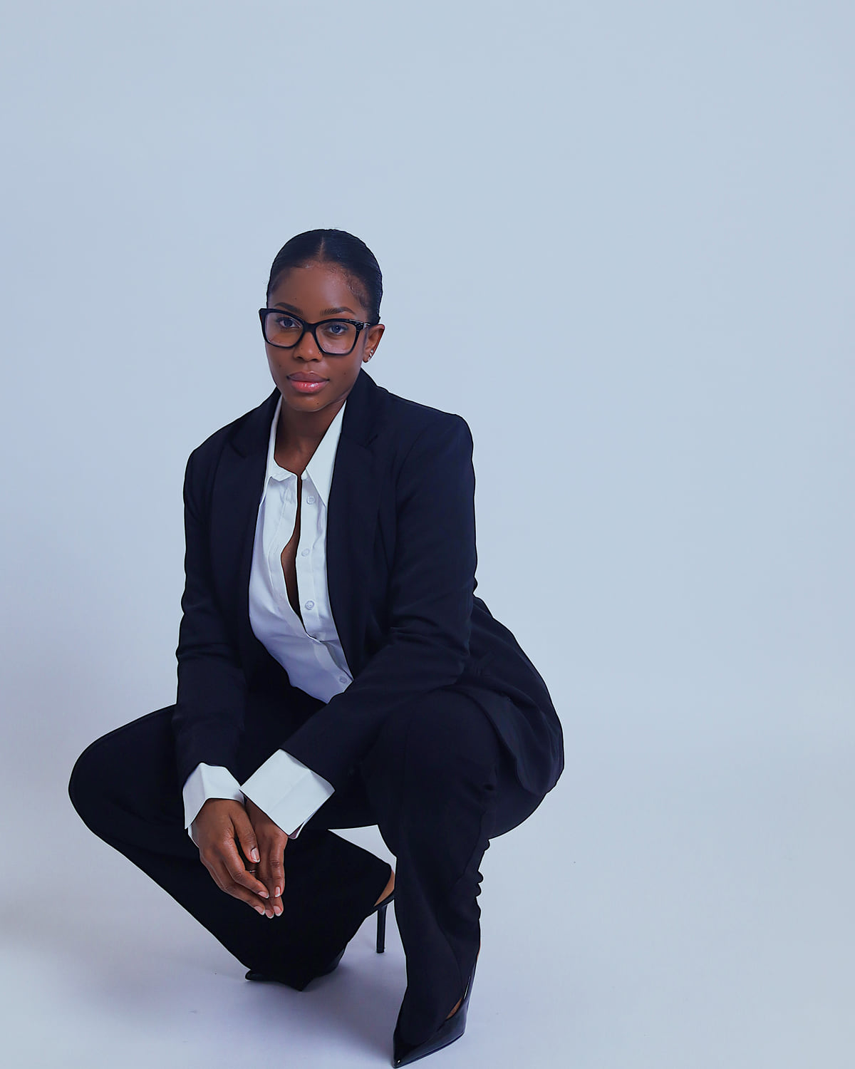 Portrait of Sohna Oulare in a crouching pose wearing a navy suit